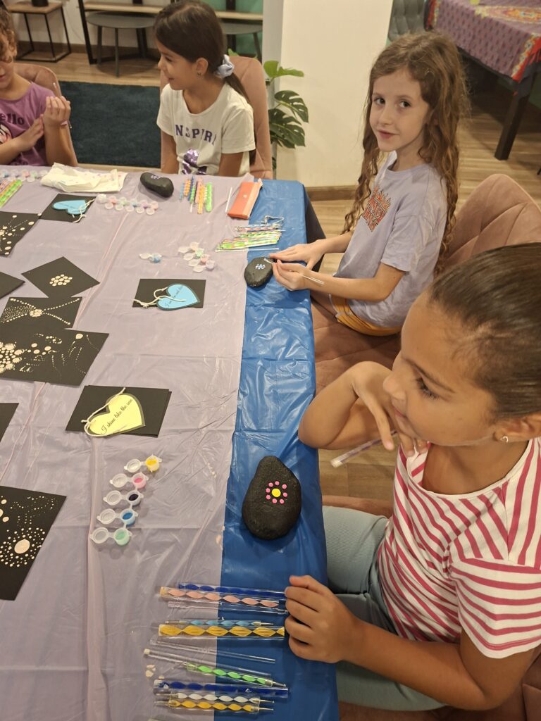 Kids enjoying a creative mandala art session with brushes, paints, and dotting tools at Café Azure Naxxar.