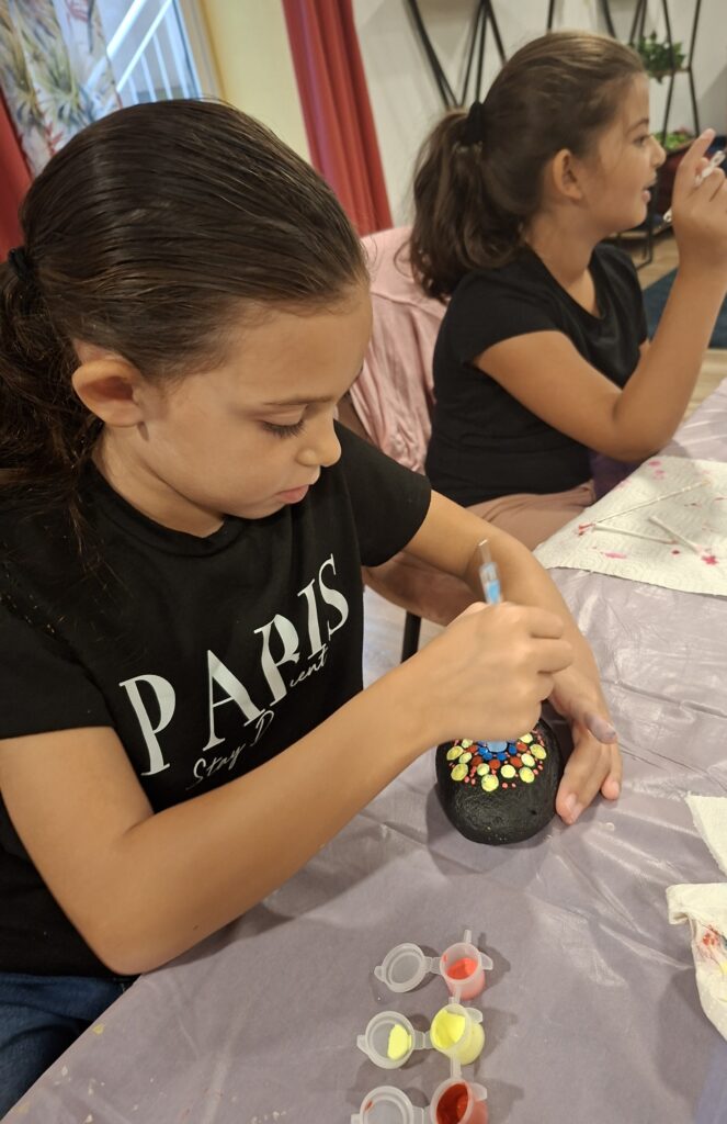 Children focused on painting mandala stones with bright colors and dotting tools, guided by Mandala Vibes in Malta.