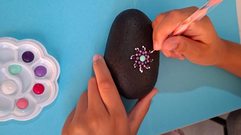 Child painting a colorful mandala dot art pattern on a stone during Mandala Dot Art Kids Workshop Malta (7+).